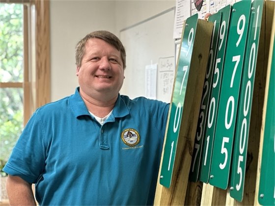 Nags Head Planner Chris Trembly stands next to address signs.